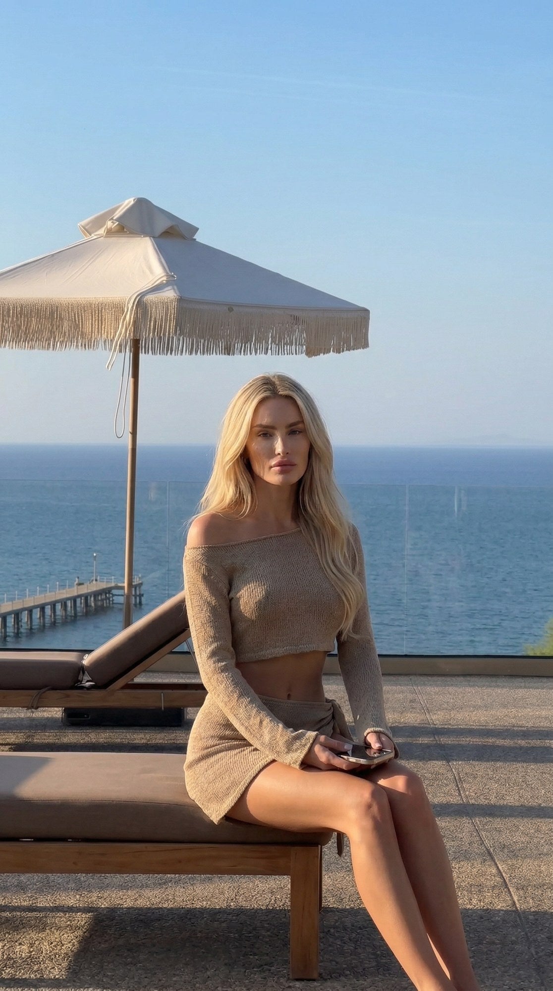 Lily Top set in sand, model seated by the sea